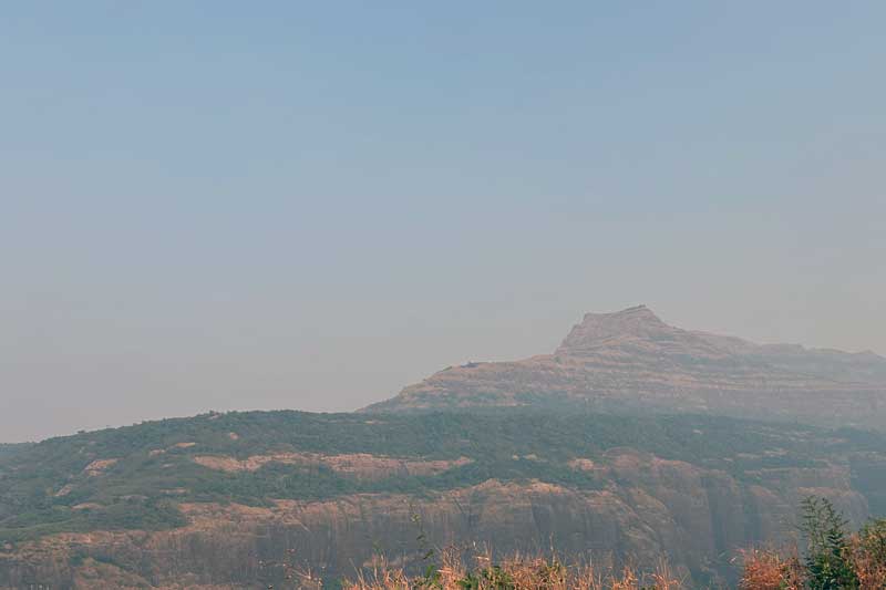 Imposing view of Jambhlya Dongar mountain as seen from the Savlya Ghat plateau, with its distinctive profile rising dramatically against the sky and dominating the landscape of the surrounding valleys.