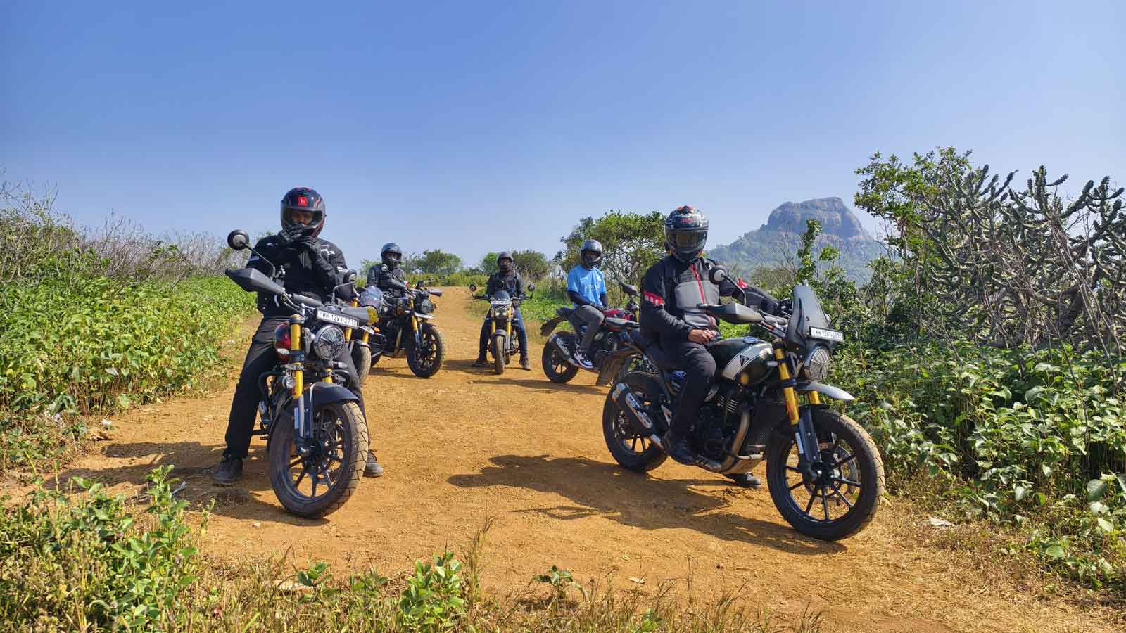 Group of six motorcycle enthusiasts standing together in a field of purple Karvi flowers near Lonavla, wearing riding gear and surrounded by the distinctive lavender blooms that appear once every seven years in the Western Ghats