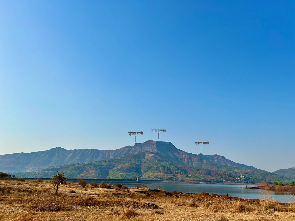 Close-up view of Torna Fort from Gunjavne Dam with Marathi text labels pointing out significant features on the fort structure, including Zunjar Machi, Bale Killa, and Budhla Machi